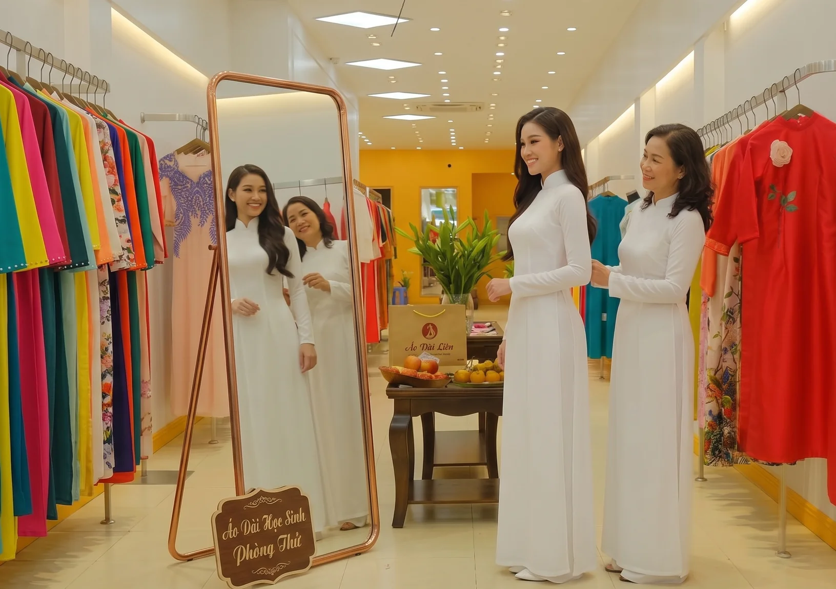 Phụ huynh tư vấn chọn áo dài học sinh cho con gái tại shop